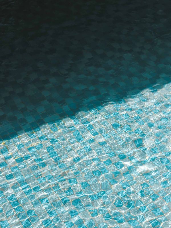 Eau claire et scintillante d’une piscine avec mosaïque bleue, mettant en avant un service professionnel d’entretien et de nettoyage de piscines à Genève par Alfredo Services.