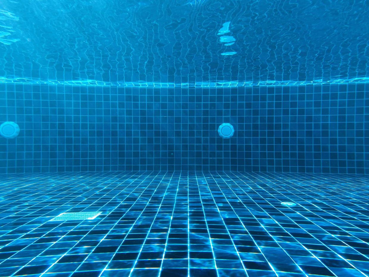 Piscine propre et claire avec mosaïque bleue sous l’eau, mettant en avant un service de gestion et d’entretien des piscines à Genève par Alfredo Services.